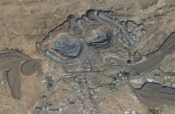 A picture showing an open-pit mining site with east and west stope surrounded by waste dump like demon’s claws and teeth